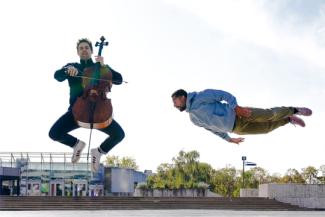 Spectacle musical interprété par Cello 360 Break à l'espace des Augustins Deux hommes dans les airs dont l'un joue du violon et l'autre est allongé