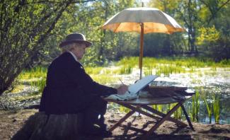 Vieille femme assis sur une table avec un parasol en train de peindre