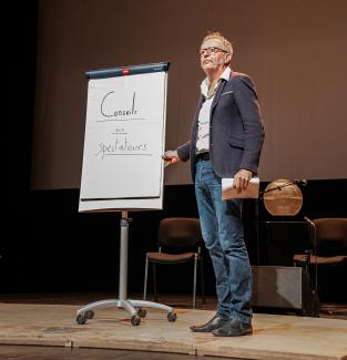 Un homme se tient sur scène avec un tableau